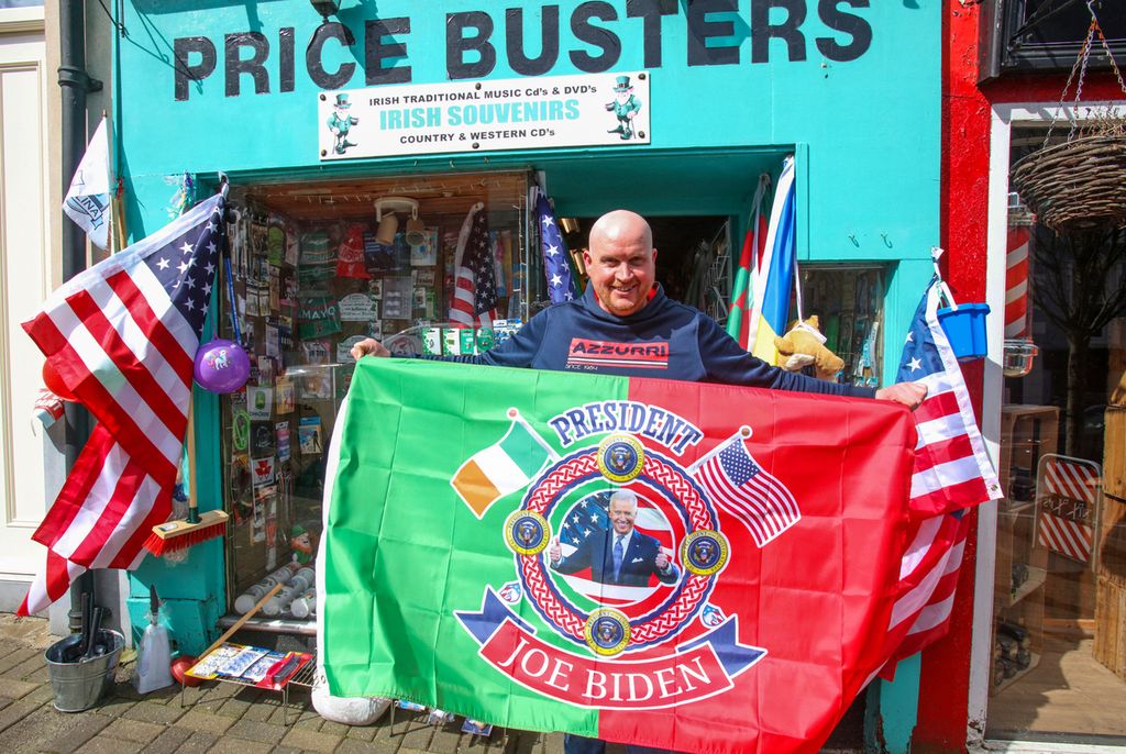 PJ Hughes berpose di luar toko suvenir miliknya di kota Ballina, Irlandia, 7 April 2023, saat kota itu bersiap menyambut Presiden AS Joe Biden yang akan datang ke kota leluhurnya itu. 