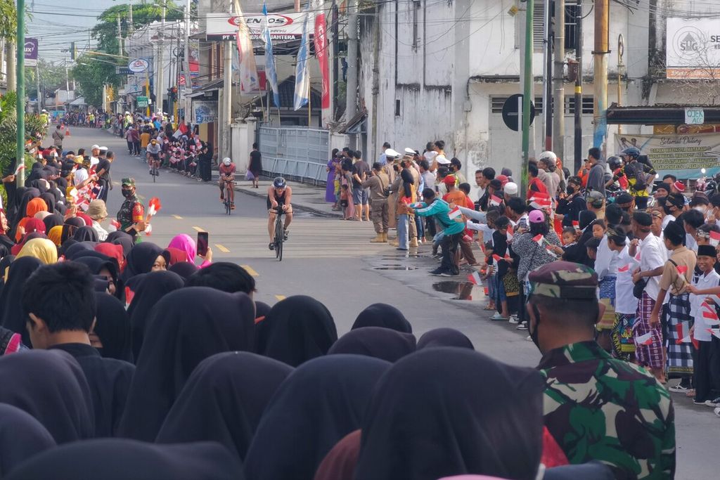 Warga Kota Mataram, Nusa Tenggara Barat, tumpah ruah di jalan untuk memberikan semangat kepada para atlet peserta Ironman 70.3 saat bersepeda melintasi kawasan Kota Tua Ampenan, Kota Mataram, Sabtu (8/10/2022). Ajang olahraga ketahanan yang memadu renang, sepeda, dan lari itu diikuti 406 atlet dari dalam dan luar negeri.