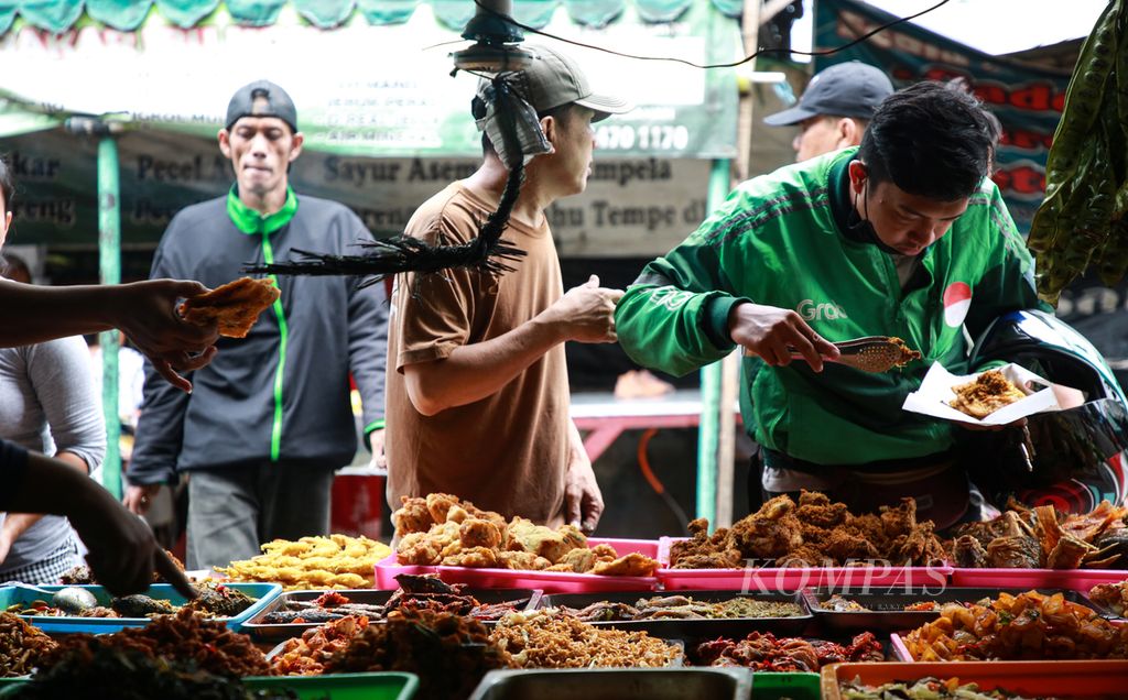 Pengemudi ojek daring memilih lauk untuk makan siang di warung makan di kawasan Petamburan, Tanah Abang, Jakarta pusat, Senin (12/9/2022).