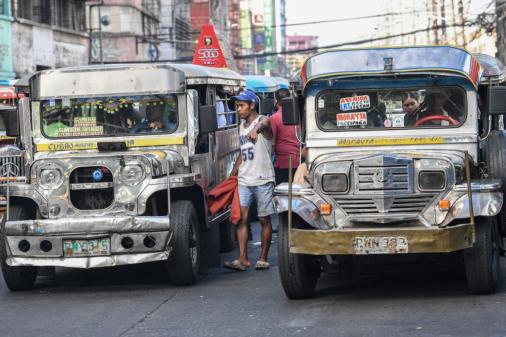 Foto yang diambil pada 5 April 2024 ini memperlihatkan seorang &quot;makelar penumpang&quot;, orang yang bertugas mencari penumpang, mengatur arus penumpang pada dua jeepney yang ada di kanan dan kirinya agar terisi penuh.  