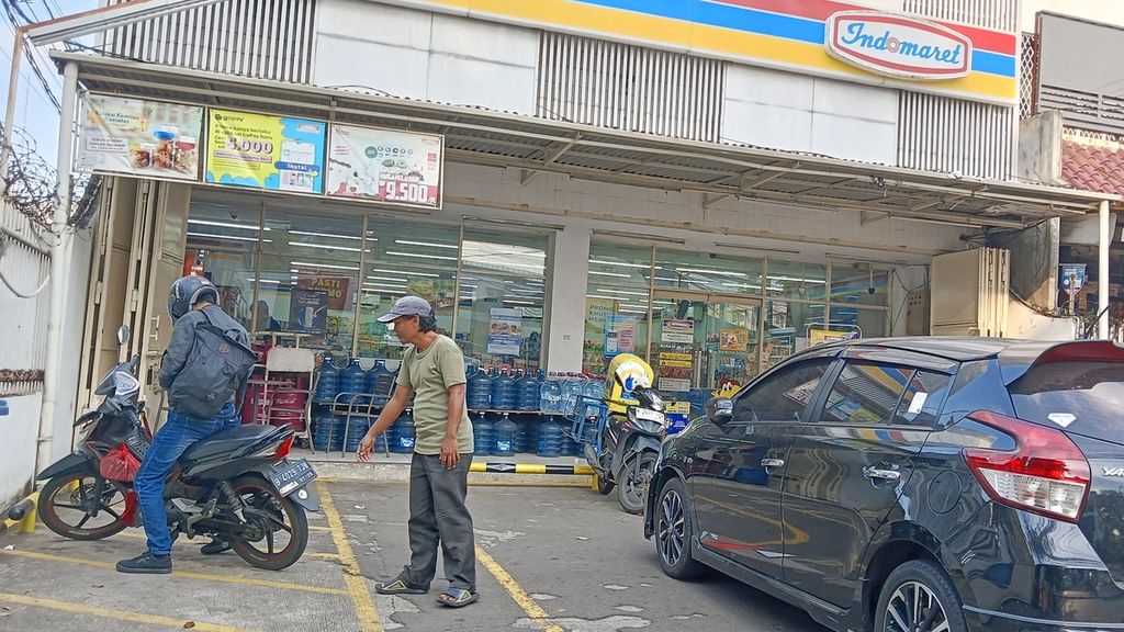 Agus (49), juru parkir di minimarket, sedang mengarahkan pengendara motor yang ingin keluar dari area parkir, di Palmerah, Jakarta Barat, Senin (13/5/2024).