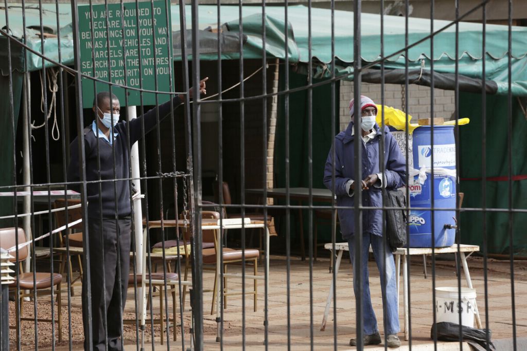 Petugas menghalau pria yang berusaha mendapatkan vaksinasi di Harare, Zimbabwe, Selasa (8/6/2021). 