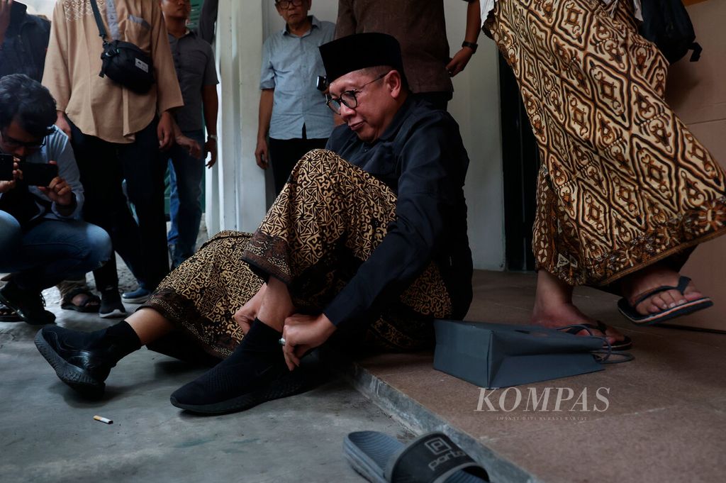 Lukman Hakim Saifuddin mengenakan sepatu setelah berkunjung ke rumah Ahmad Mustofa Bisri di Kabupaten Rembang, Jawa Tengah, bersama sejumlah tokoh untuk membahas berbagai persoalan kebangsaan dan demokrasi, Minggu (12/11/2023). 