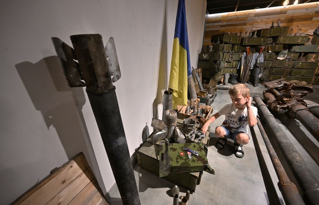 Seorang anak laki-laki sedang melihat amunisi dan alat persenjataan bekas lainnya di Museum Memori di Bucha, Kyiv, 30 Juni 2023.