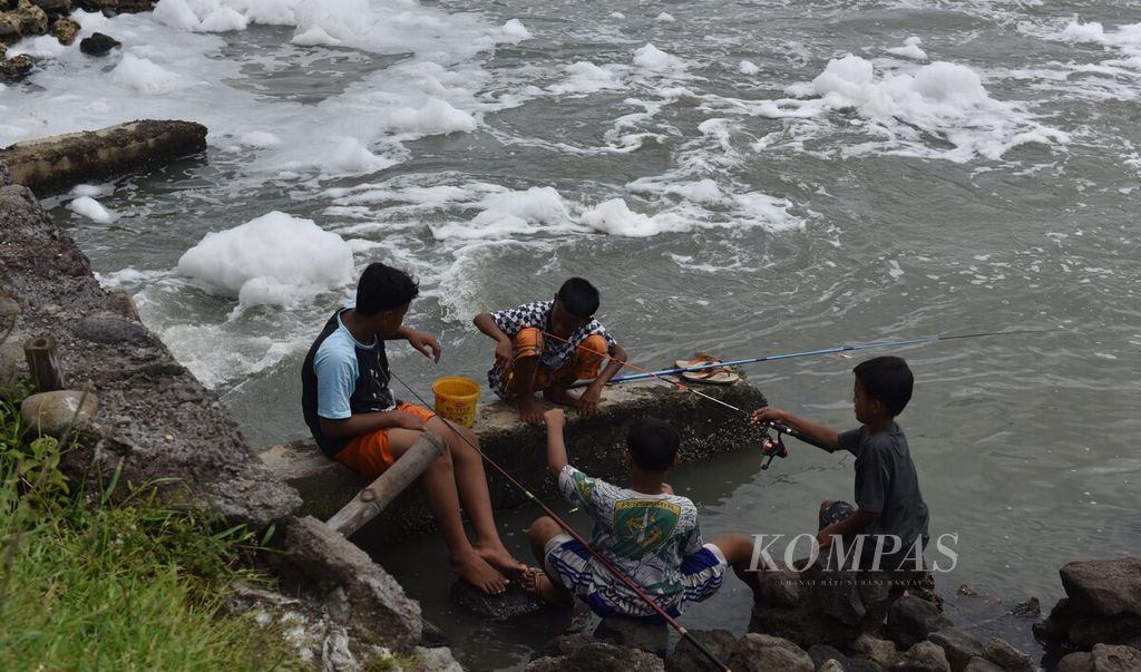 Sejumlah anak memancing di pinggir pantai yang tercemar limbah detergen di Kota Surabaya, Jawa Timur, Senin (28/2/2022). Rendahnya kesadaran untuk menjaga lingkungan membuat Selat Madura kini tercemar limbah. Sebagian besar limbah adalah limbah rumah tangga. 