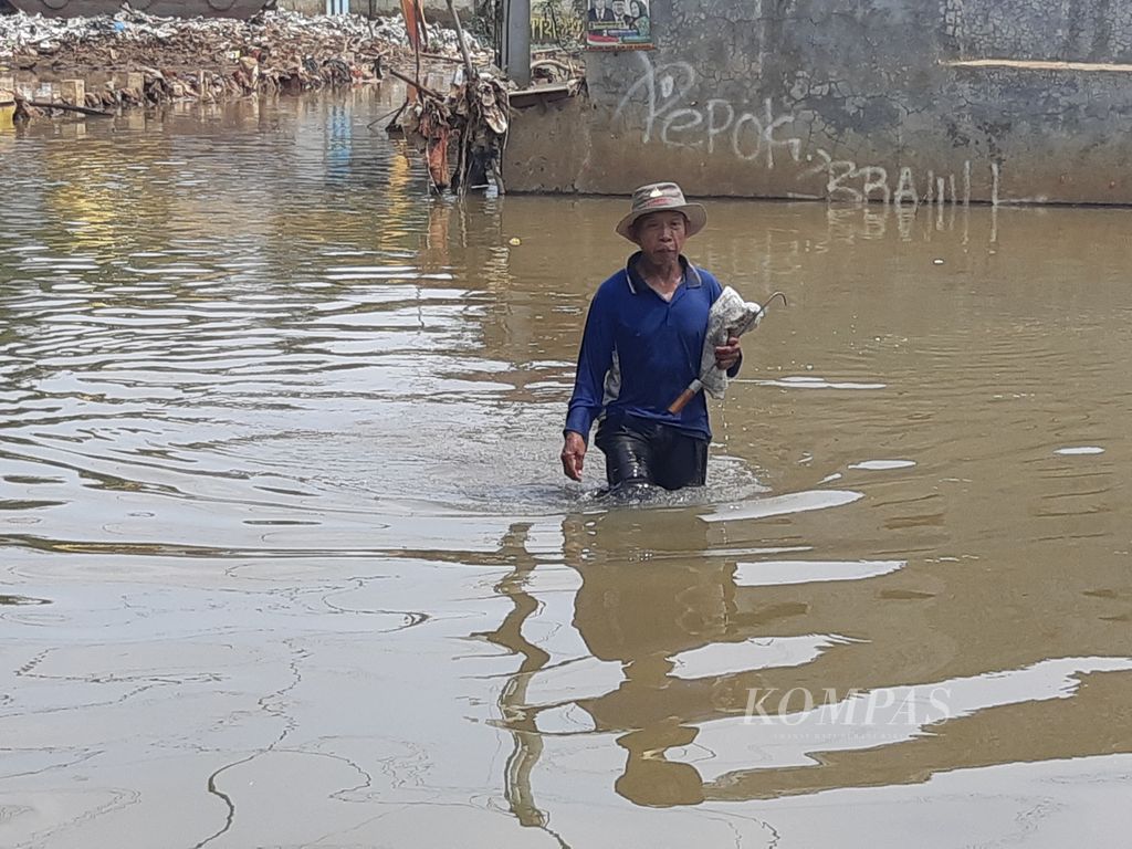 Sarmili had to brave the flood caused by the access road from Pasir Putih area, Sawangan, towards Jalan Bulak Barat, Cipayung District, Depok City, West Java, submerged by a flood with a height of up to 1.5 meters on Monday (29/4/2024).