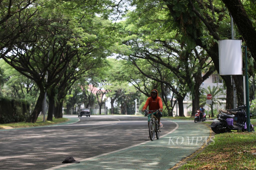 <i>Green tunnel</i> atau kanopi alami dari naungan vegetasi pohon-pohon trembesi (<i>Samanea saman</i>) di jalan depan kluster Sutera Narada, Alam Sutera, Tangerang Selatan, Banten, Senin (11/12/2023). Keberadaan kanopi alami ini membuat jalanan menjadi teduh dan sejuk meski pada siang hari. 
