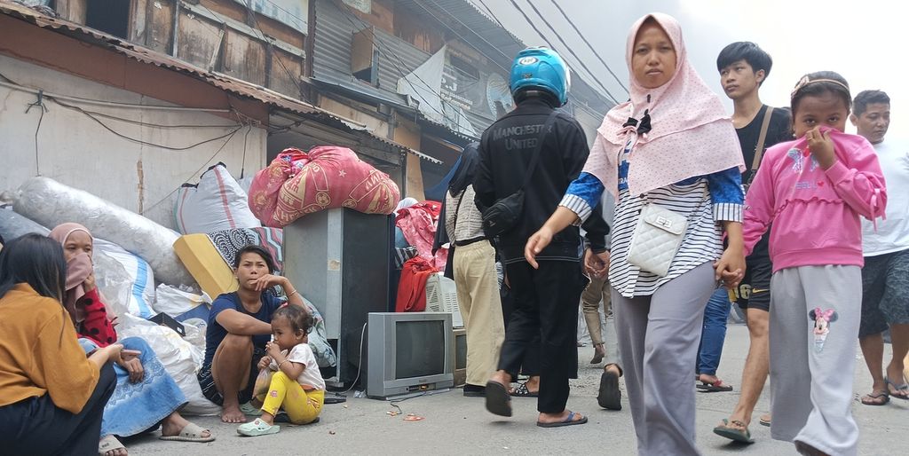 Warga menjaga barang yang mereka selamatkan dari peristiwa kebakaran di RW 003 Jalan Kapuk Utara 2, Kapuk Muara, Penjaringan, Jakarta Utara, yang ludes terbakar, Minggu (30/7/2023).