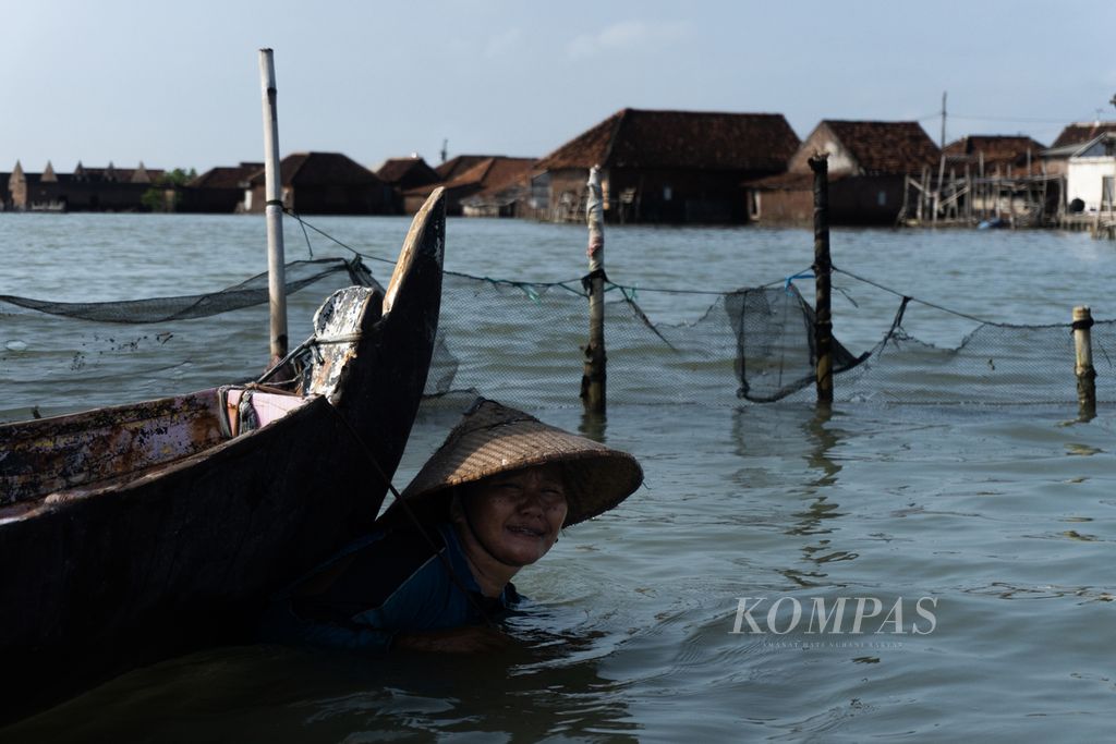 Sunarti (50), perempuan nelayan Timbulsloko, mendorong kapal.