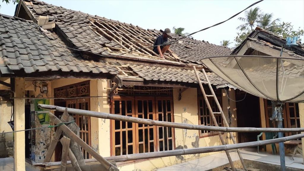 Warga memperbaiki genteng rumah yang rusak akibat gempa.