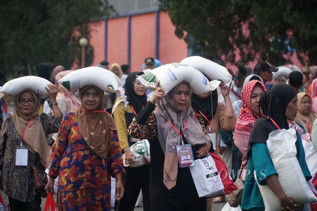 Warga menjunjung beras dan membawa sembako bantuan yang diserahkan Presiden Joko Widodo kepada 500 keluarga di Gudang Bulog Sumatera Barat (Sumbar), Kota Padang, Sumbar, Rabu (25/10/2023). 