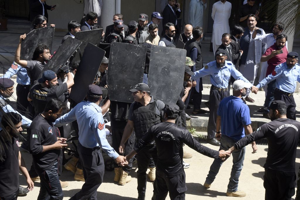 Pasukan keamanan dengan tameng antipeluru mengawal mantan Perdana Menteri Imran Khan saat tiba di pengadilan di Islamabad, Pakistan, 9 Mei 2023. Ia ditangkap saat kemunculannya dengan tuduhan korupsi. 