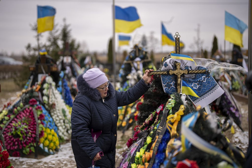 Maria Kurbett (77) menangis di depan makam putranya, seorang tentara Ukraina yang tewas dalam pertempuran di Bakhmut, Jumat (24/2/2023). (AP Photo/Emilio Morenatti)