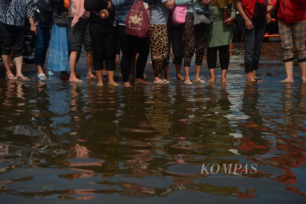 Factory workers wait for boat transportation to the bonded area which is still submerged by tidal flooding at Tanjung Emas Port, Semarang City, Central Java, Friday (27/5/2022). The company's management mobilized them to clean and tidy up factory tools that were ravaged by the tidal flood.