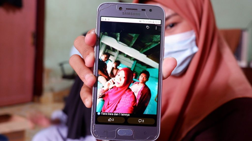 Hidayatul Amni (22) memperlihatkan foto Julia Ningsih (19), istri kakaknya Junaidi (26) di Desa Dasan Borok, Kecamatan Suralaga, Kabupaten Lombok Timur, Nusa Tenggara Barat, Jumat (21/1/2022). Julia Ningsih yang berangkat ke Malaysia bersama Junaidi, merupakan salah satu korban meninggal dunia dalam kecelakaan kapal pengangkut Pekerja Migran Indonesia non prosedural di perairan Johor, Malaysia, pada pertengahan Desember 2021 lalu.