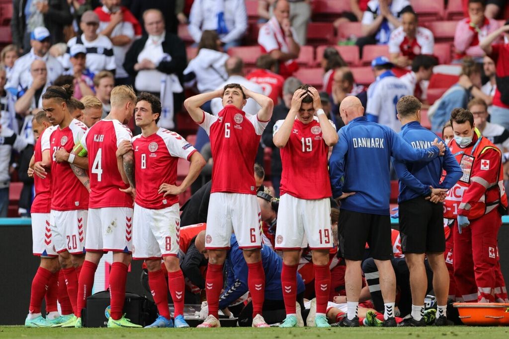 Para pemain timnas Denmark mengelilingi Christian Eriksen yang sedang tidak sadarkan diri dan mendapat perawatan dari paramedis, pada laga pembukaan Piala Eropa grup B, saat Denmark melawan Finlandia, di Stadion Parken, Copenhagen, 12 Juni 2021.