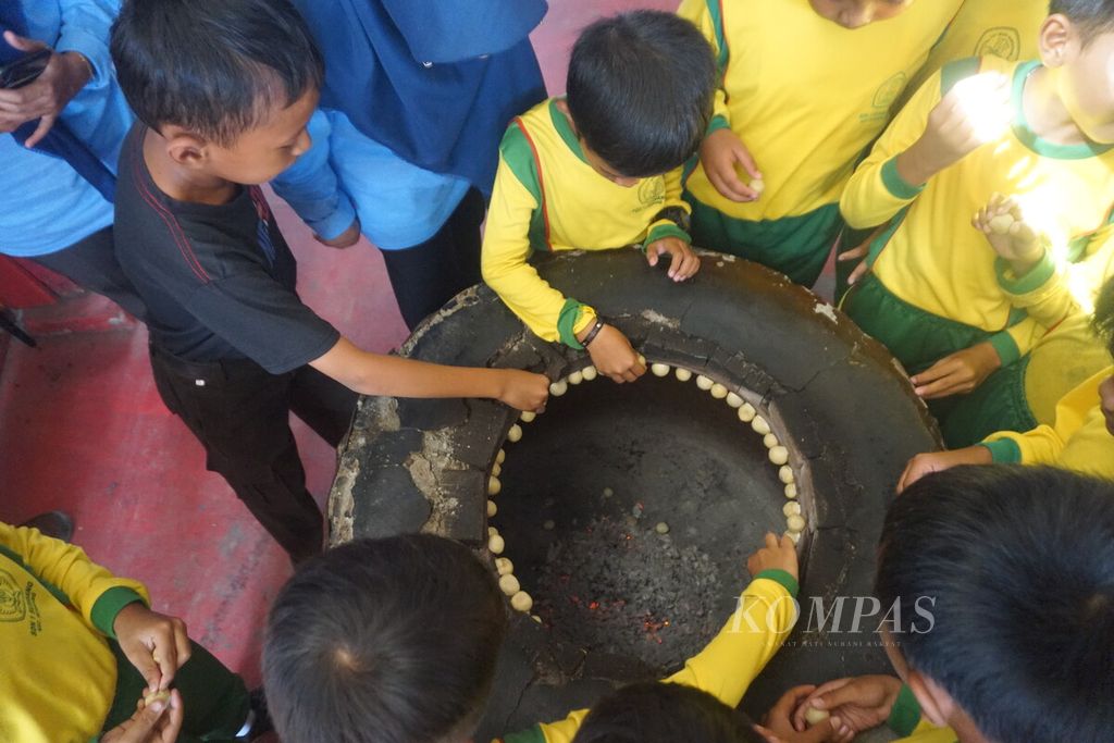 Anak-anak pelajar SDN 1 Sumbang menata mino dalam gentong atau tungku untuk dipanggang 10 menit di Desa Pekunden, Banyumas, Jawa Tengah, Jumat (1/3/2024).