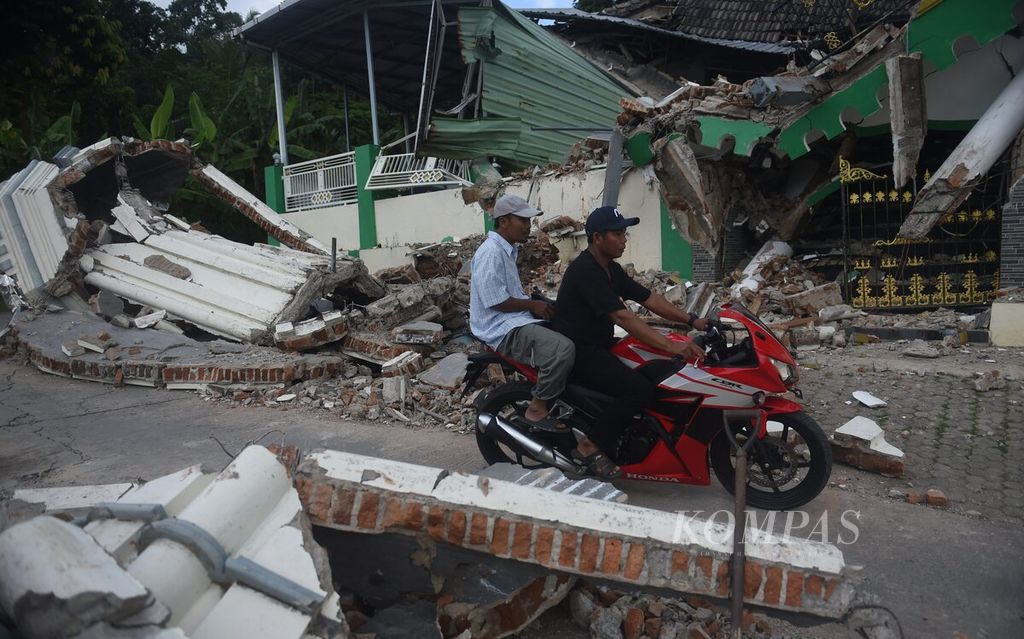 Warga melintas di depan Masjid Al-Muhajirin yang rusak oleh gempa di Desa Gunungteguh, Kecamatan Sangkapura, Pulau Bawean, Kabupaten Gresik, Jawa Timur, Minggu (24/3/2024). 