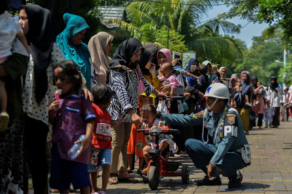 Prajurit Polisi Militer TNI Angkatan Laut menenangkan seorang anak yang menangis saat mangantre bersama ibunya di kawasan Pulau Untung Jawa, Kepulauan Seribu, Jakarta, Senin (15/5/2023). 