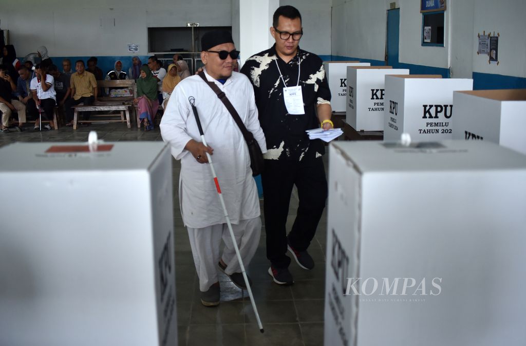 Warga tunanetra didampingi petugas KPPS akan memasukkan kertas suara ke kotak suara seusai menjalani pemungutan suara Pemilihan Umum 2024 di Tempat Pemungutan Suara (TPS) 37, RT 030 RW 005, Kelurahan 8 Ilir, Kecamatan Ilir Timur 3, Palembang, Sumatera Selatan, Rabu (14/2/2024).