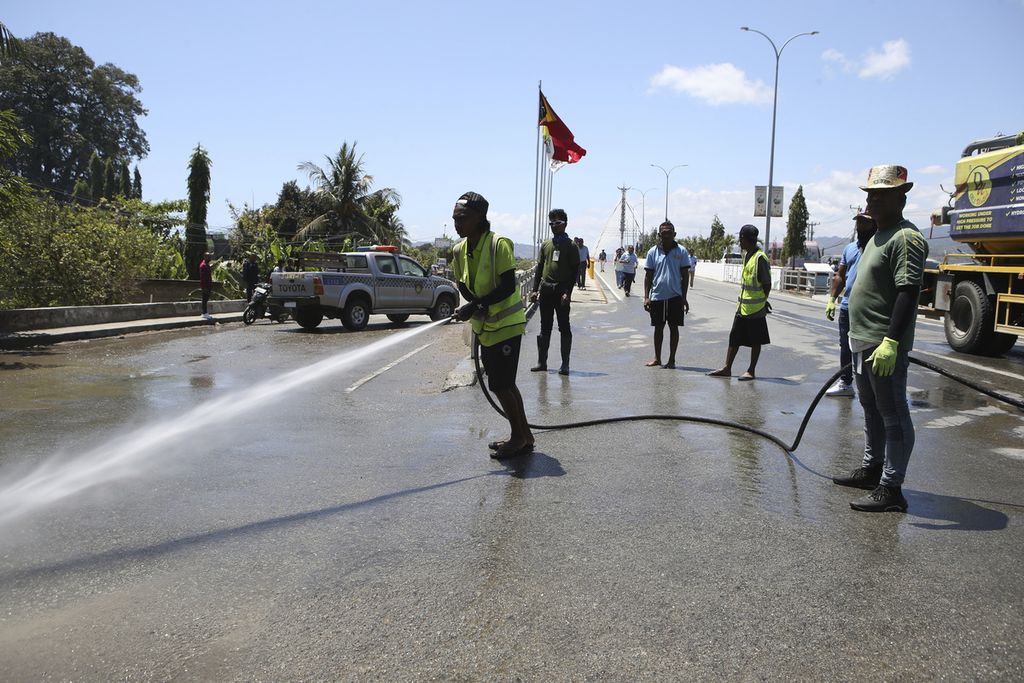 Para pekerja membersihkan jalan dengan air sebagai persiapan menyambut kedatangan Paus Fransiskus di Dili, Timor Leste, Kamis (5/9/2024). 