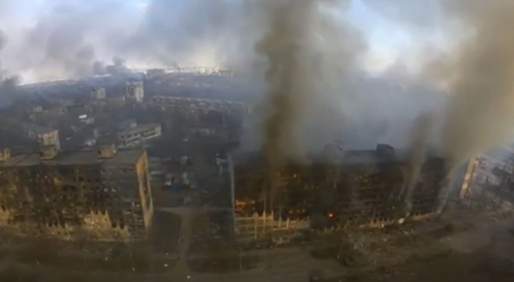 Potongan gambar yang diambil dari rekaman video milik Batalion Azov, militer Ukraina yang ditempatkan di Kota Mariupol, Ukraina, Senin (14/3/2022), memperlihatkan deretan gedung mengeluarkan asap seusai diserang menggunakan artileri berat oleh militer Rusia. 