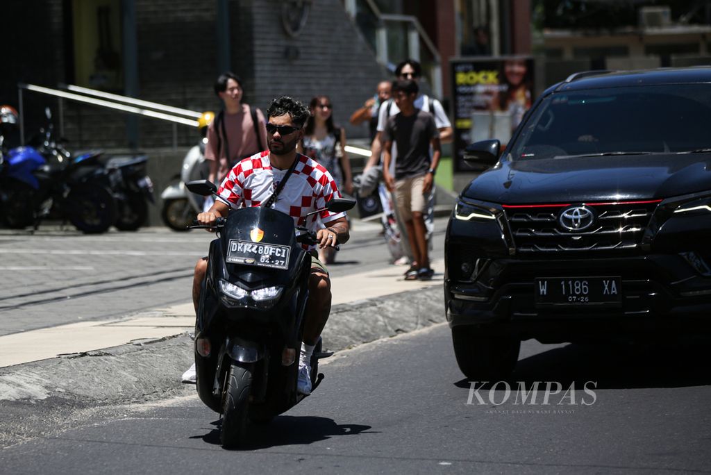 A foreign tourist rides a motorbike without wearing a helmet in the Kuta area, Bali, Saturday (18/3/2023).