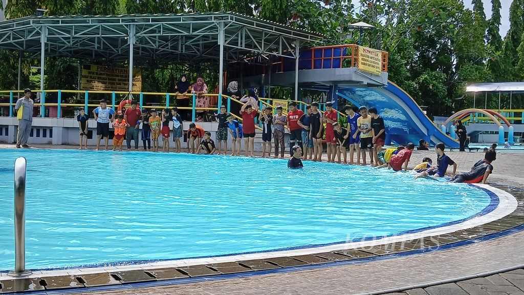 Anak-anak sedang berlatih renang dengan diawasi pelatih renang, penjaga keselamatan (<i>lifeguard</i>), serta orangtuanya, di kolam renang Taman Tirta Mas (Palem Indah), Pondok Kelapa, Duren Sawit, Jakarta Timur, Selasa (13/2/2024).