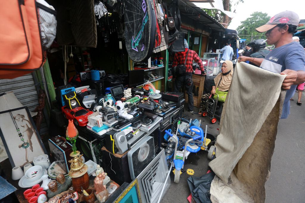 Pedagang pasar loak Jembatan Item, Jatinegara, Jakarta Timur, menutup dagangannya dengan terpal saat gerimis turun, Minggu (20/2/2022). Pasar ini menjadi gudang barang bekas yang kerap diburu pembeli dari berbagai daerah dengan harga yang murah.