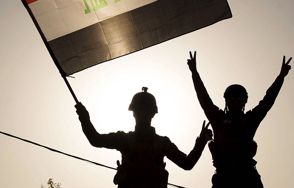 Polisi federal Irak mengibarkan bendera nasional Irak saat merayakan keberhasilan pasukan Pemerintah Irak merebut kembali kota Mosul dari tangan kelompok Negara Islam di Irak dan Suriah (NIIS), di Kota Tua, Mosul, Irak, Minggu (9/7). Irak mendeklarasikan kemenangan atas NIIS di Mosul setelah pertempuran selama sekitar sembilan bulan. 