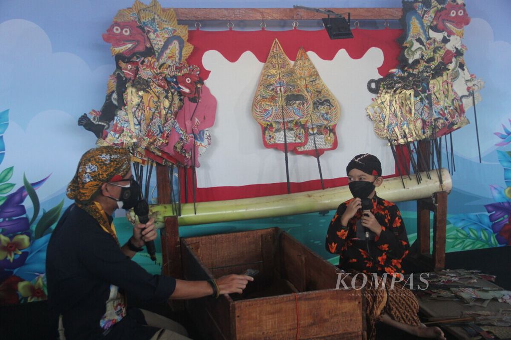 Menteri Pariwisata dan Ekonomi Kreatif Sandiaga Uno berbincang dengan seorang dalang cilik saat berkunjung ke Kampung Wisata Rejowinangun, Kota Yogyakarta, Jumat (8/10/2021).