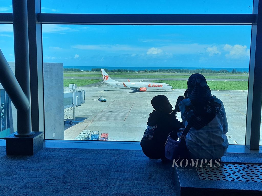 Seorang ibu bersama anaknya menyaksikan pesawat yang akan lepas landas di Bandara Internasional Yogyakarta, Rabu (3/4/2024), tujuh hari menjelang Idul Fitri 2024.