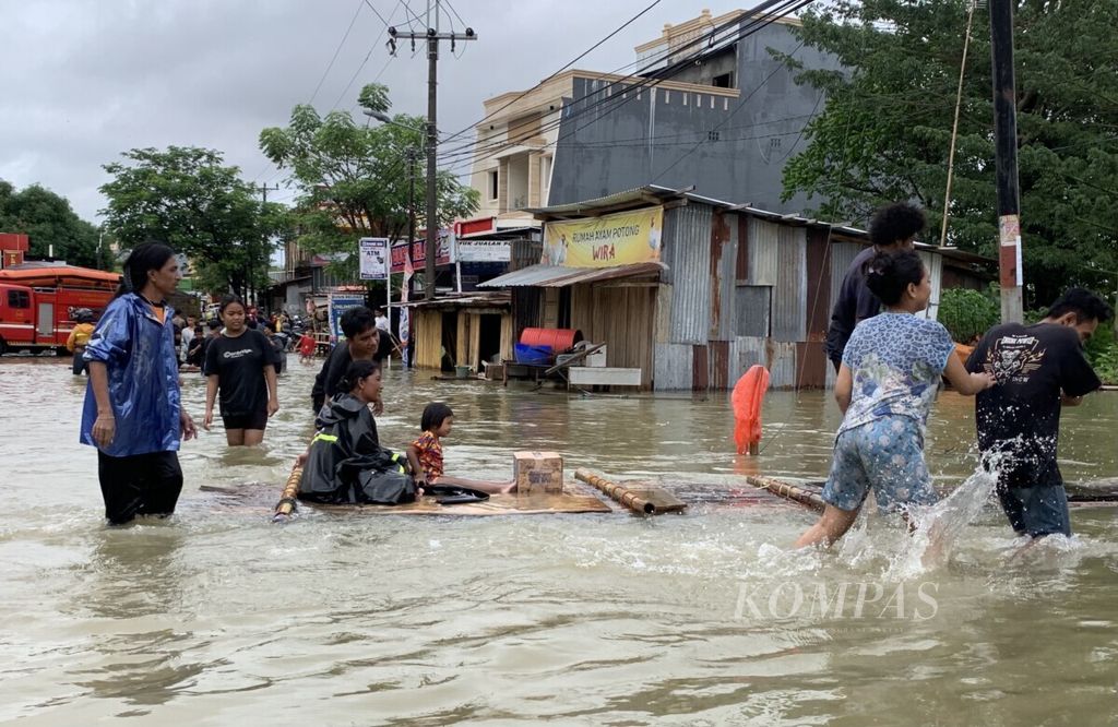 Warga kompleks BTP Kecamatan Biringkanaya menggunakan rakit menuju tempat aman, Selasa (7/12/2021). Banjir parah di Makassar membuat sebagian warga harus dievakuasi.