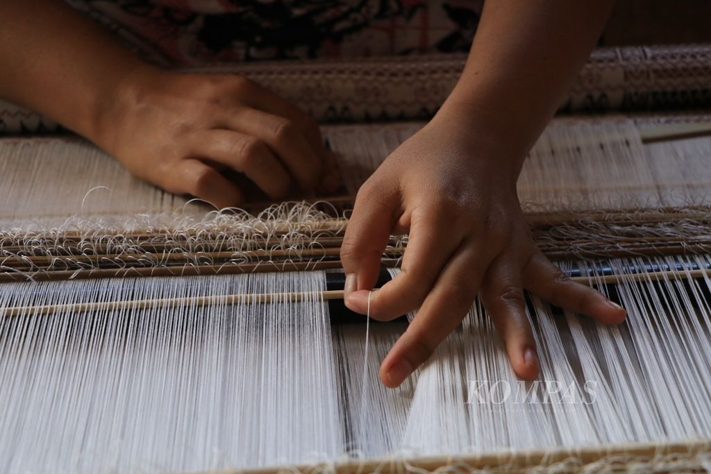 Nurmasito Sihombing (38) menenun ulos di Desa Enda Portibi, Kecamatan Siatas Barita, Kabupaten Tapanuli Utara, Sumatera Utara, Selasa (12/10/2021). Para penenun kini semakin bergairah karena mendapat harga yang lebih baik setelah menghasilkan kain berkualitas dan bisa memasuki industri mode.