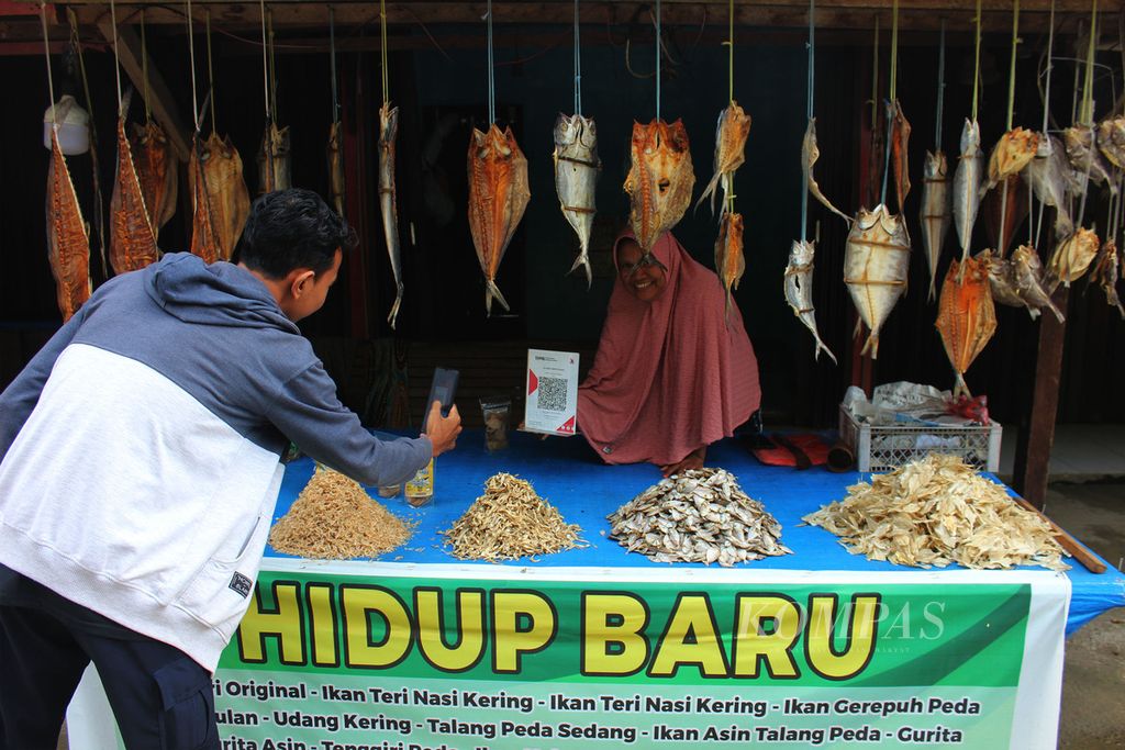 Buyers scan barcode to pay when purchasing micro, small, medium enterprises (MSME) products at the salted fish sales center in Leupung district, Aceh Besar regency, Aceh, (21/6/2022). Coastal businessmen in Aceh Besar have started implementing digitalization systems to facilitate transactions and sales.
