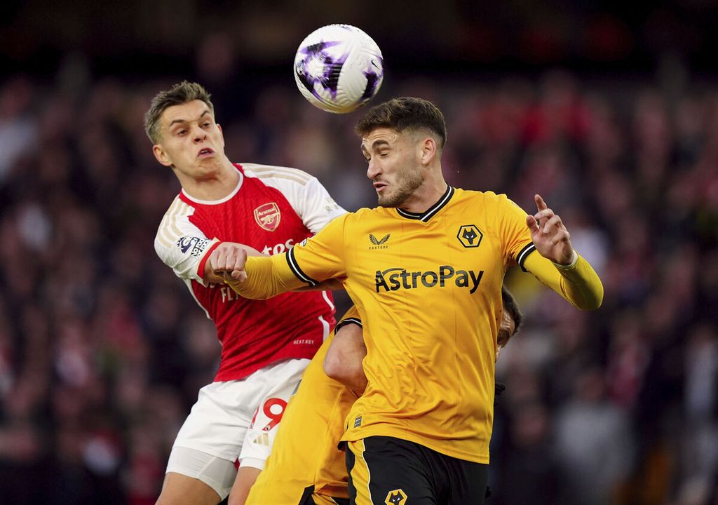 Pemain Arsenal, Leandro Trossard (kiri), dan pemain Wolverhampton Wanderers, Santiago Bueno, berebut bola dalam laga Liga Inggris di Stadion Molineux, Wolverhampton, Minggu (21/4/2024) dini hari WIB. Arsenal menang 2-0.