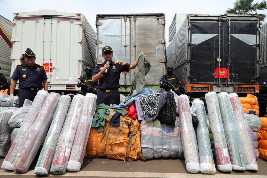 Direktur Jenderal Bea dan Cukai Heru Pambudi (kanan) menunjukkan salah satu pakaian ilegal di Kantor Direktorat Jenderal Bea dan Cukai, Jakarta Timur, Rabu (11/3/2020). Atas penindakan tersebut, Bea dan Cukai mengamankan 874 bale pakaian, 118 set ban, dan 57 roll karpet yang dibawa menggunakan enam truk Fuso. Barang tersebut diduga berasal dari luar negeri tanpa dilengkapi dokumen yang sah. Total perkiraan nilai barang Rp 2.926.400.000. Hingga saat ini, penelitian secara mendalam terus dilakukan guna menemukan pelaku atau pemilik barang. Upaya yang dilakukan Bea dan Cukai tersebut untuk menciptakan persaingan usaha yang sehat dan mendorong perekonomian dalam negeri.