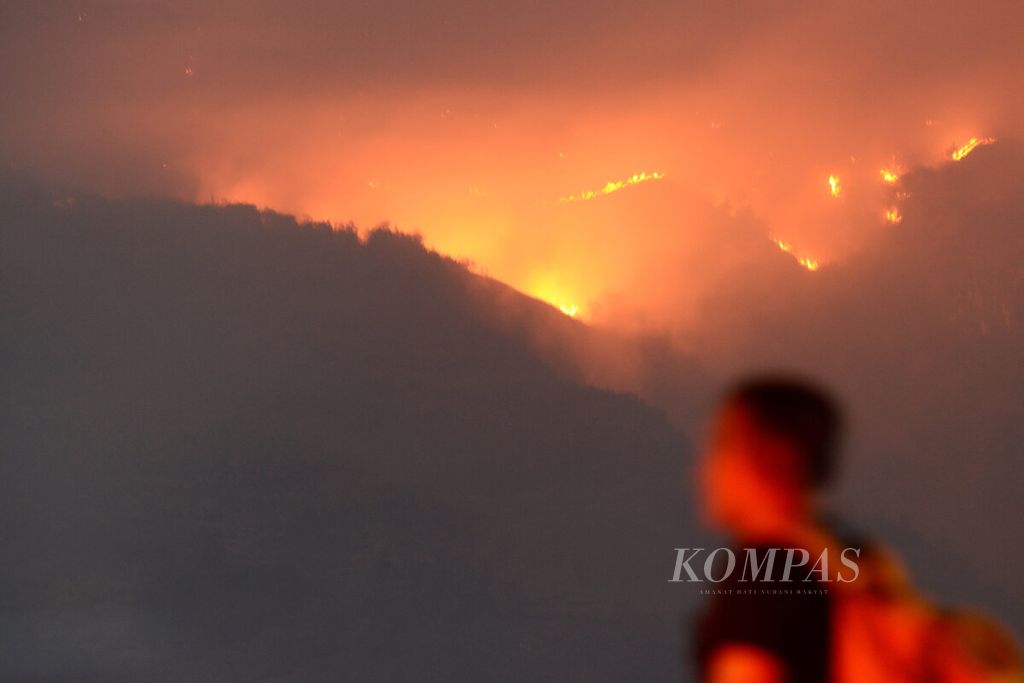 Warga dengan latar belakang lereng Gunung Merbabu yang terbakar terlihat Desa Batur, Kecamatan Getasan, Kabupaten Semarang, Jawa Tengah, Sabtu (28/10/2023). 
