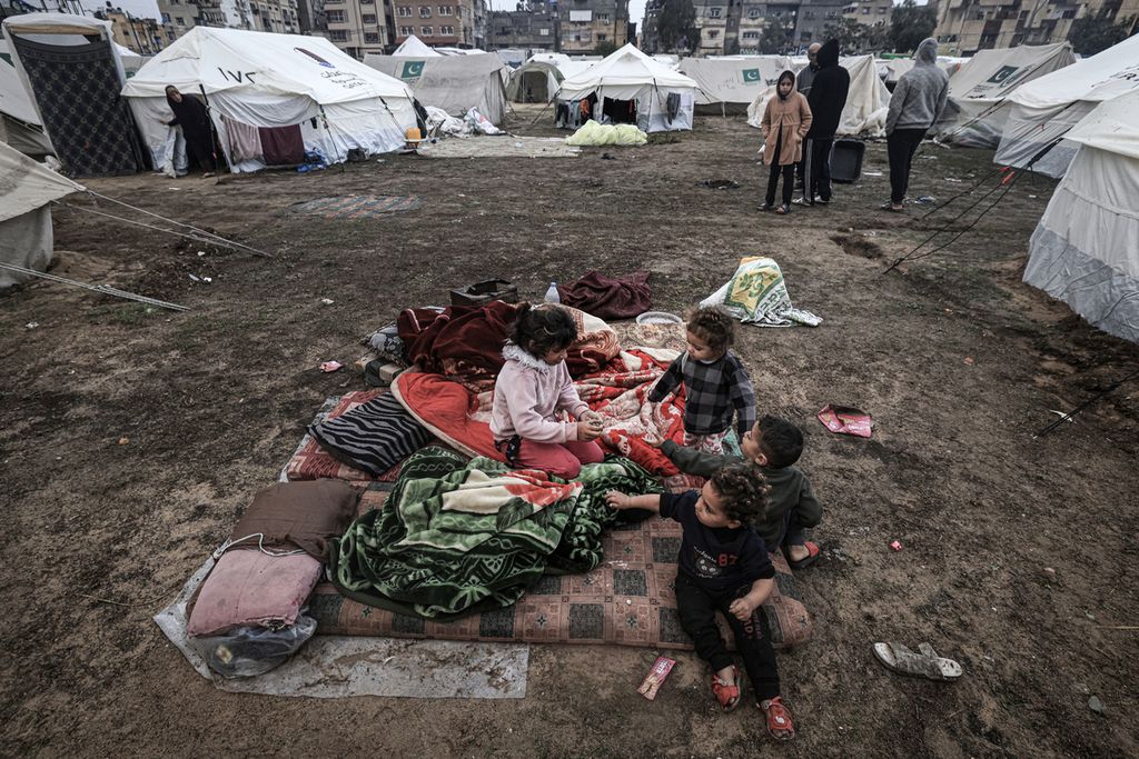 Anak-anak pengungsi Gaza tidur di luar tanpa tenda yang bisa melindungi dari hujan di kamp pengungsian di Rafah, Jalur Gaza, Rabu (13/12/2023). 