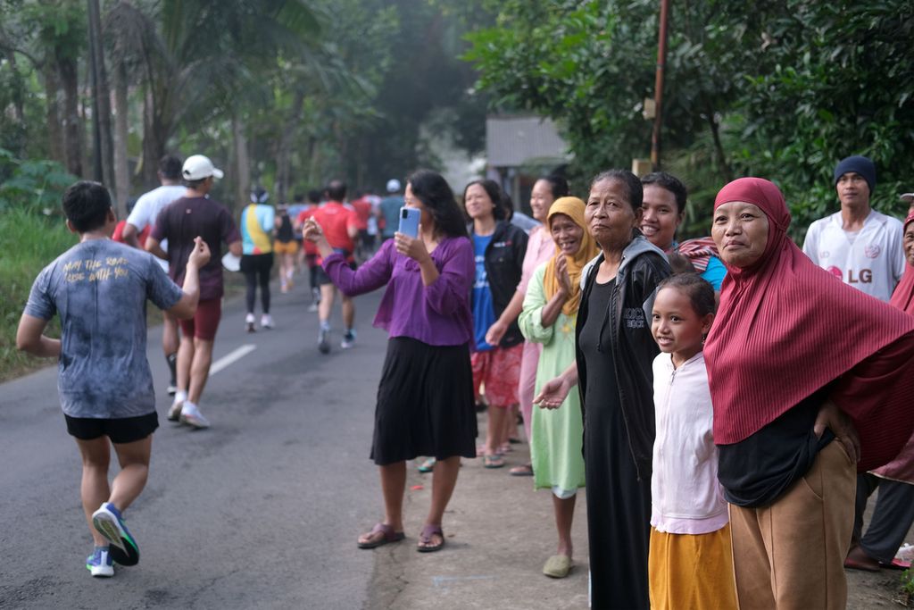 Warga menonton pelari yang menyelesaikan Borobudur Marathon 2022 Powered by Bank Jateng kategori Tilik Candi yang melewati depan rumah mereka di sekitar Kompleks Candi Borobudur, Magelang, Jawa Tengah, Minggu (12/11/2022). 