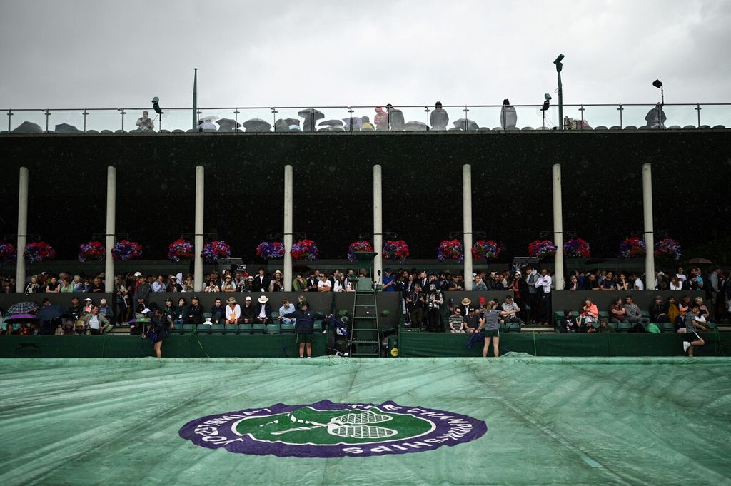 Petugas menarik terpal penutup di lapangan 8 saat hujan turun pada hari ketiga Kejuaraan Wimbledon 2023, Rabu (5/6/2023). 