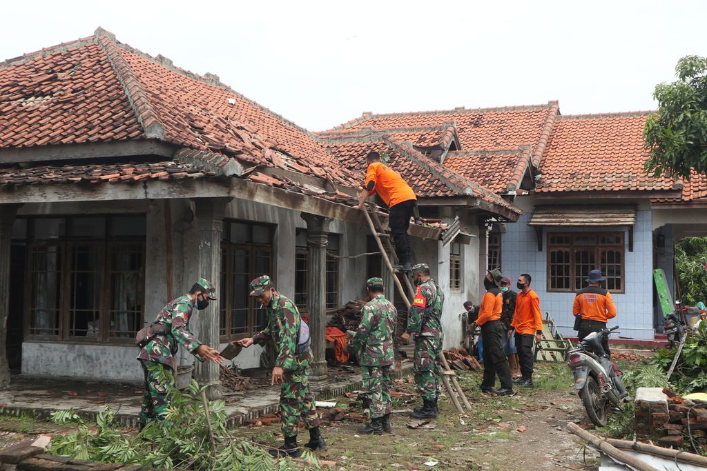 Polisi dan TNI membantu membenahi atap rumah warga yang rusak dihantam puting beliung di Desa Slangit, Kecamatan Klangenan, Kabupaten Cirebon, Jawa Barat, Minggu (3/1/2021). Puting beliung yang menerjang desa itu pada Sabtu (2/1/2021) sore merusak 278 rumah dan menyebabkan 22 orang luka-luka.