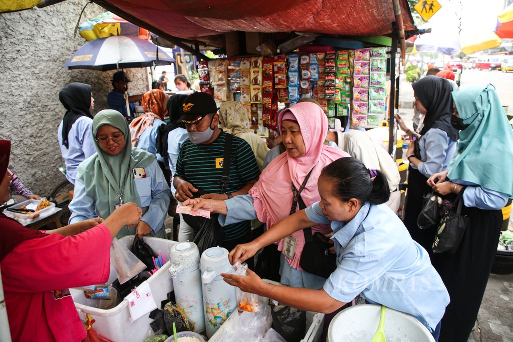 Buruh berbelanja minuman dari pedagang kaki lima di luar area pabrik saat jam makan siang di kawasan Karawaci, Kota Tangerang, Banten, Rabu (22/11/2023). 