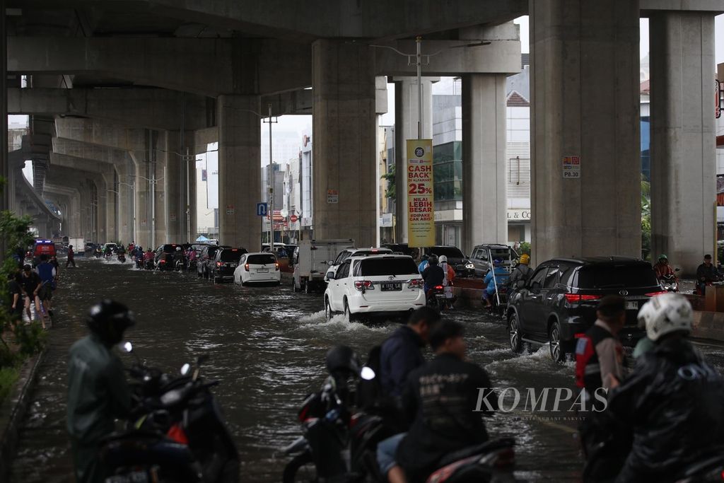 Pengguna jalan berusaha melalui Jalan Boulevard Barat Raya, Kelapa Gading, Jakarta, yang tergenang air, Kamis (29/2/2024).