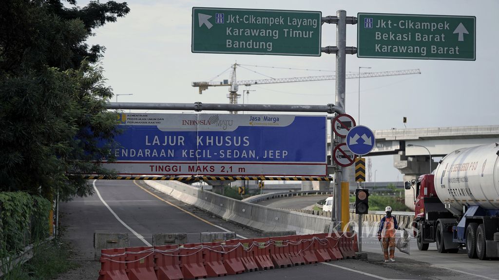 ILUSTRASI. Petugas penyapu jalan melintas di depan gerbang Jalan Tol Layang Jakarta-Cikampek yang ditutup di kawasan Simpang Susun Cikunir, Kota Bekasi, Jawa Barat, Jumat (24/4/2020). 
