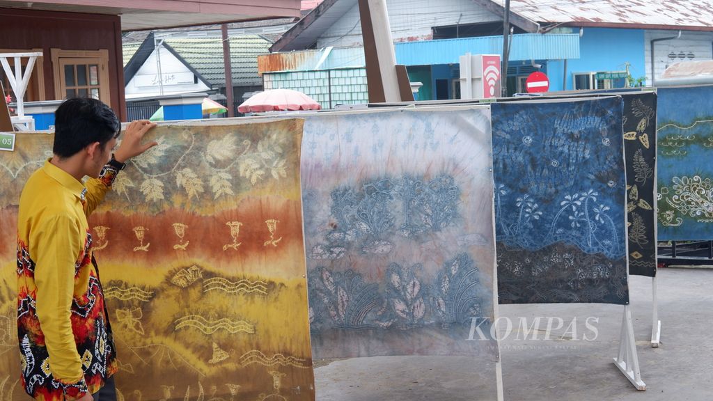 Pengunjung memperhatikan kain sasirangan dengan pewarnaan alami yang dipajang dalam Lomba Desain Motif Sasirangan Se-Kota Banjarmasin di Banjarmasin, Kalimantan Selatan, Kamis (5/3/2020). 