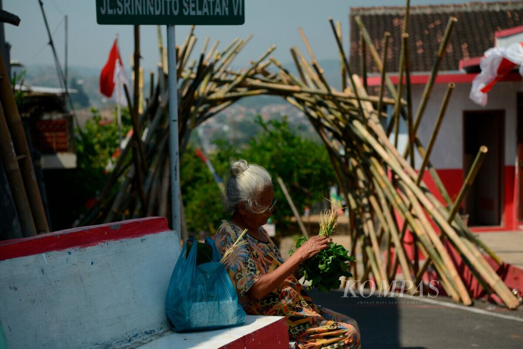 Warga membersihkan sayur dengan latar belakang karya instalasi dari bambu yang merupakan bagian dari pameran Arus Bukit di Kampung Ngemplak Simongan, Kota Semarang, Jawa Tengah, Sabtu (24/8/2019). Kegiatan tersebut merupakan bagian dari ekspresi seniman jalanan yang menampilkan seni mural dan instalasi. Mereka juga melibatkan warga kampung dalam berkegiatan seni.