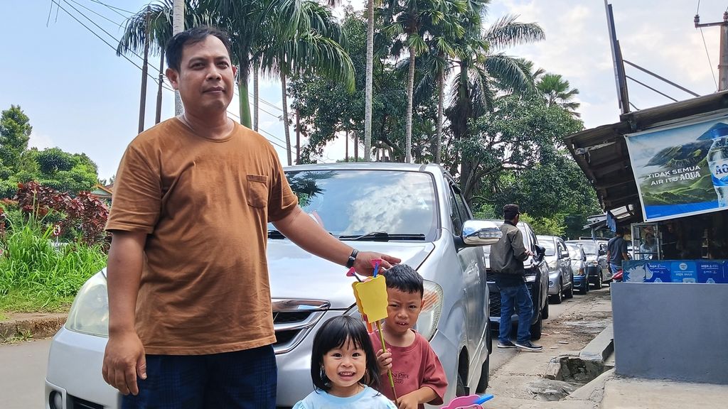 Joko Purnomo (41), wisatawan asal Jakarta, tertahan di jalan umum di sisi ruas Gerbang Tol Jagorawi, Sabtu (13/4/2024)