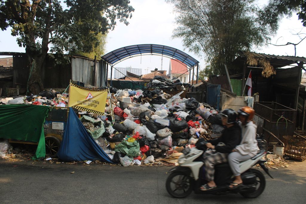 Sejumlah warga melewati tempat pembuangan sampah yang menumpuk di Kecamatan Sumur Bandung, Kota Bandung, Jawa Barat, Kamis (31/8/2023).