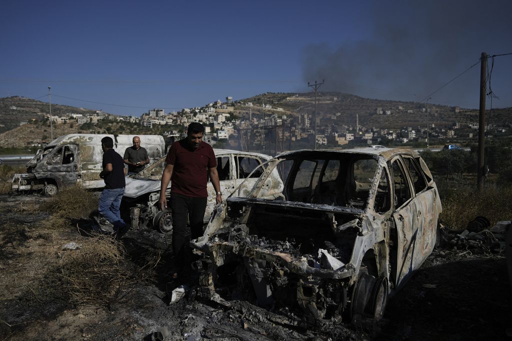 Beberapa pria memeriksa puing mobil-mobil yang dibakar, diduga oleh para pemukim Israel, di Al-Lubban Al-Gharbi, wilayah pendudukan Tepi Barat, Rabu (21/6/2023). 